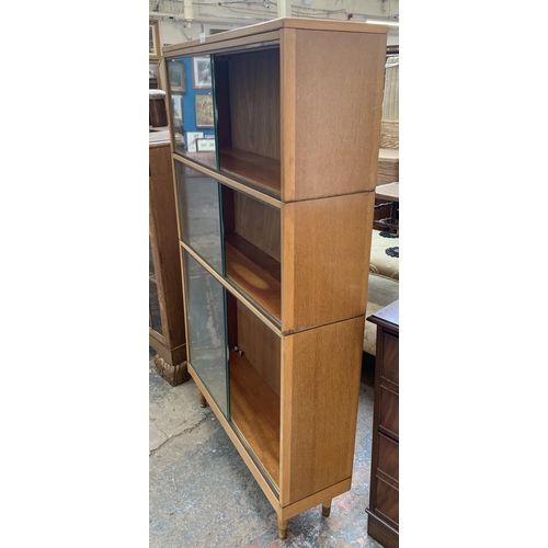 60 - A mid 20th century light oak three section stacking bookcase with sliding glazed doors - 144cm high ... 