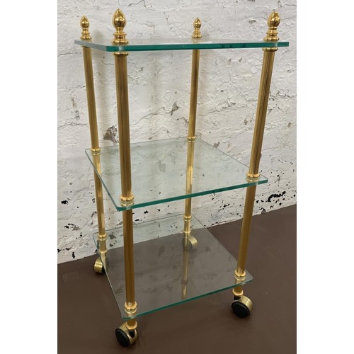 55 - A vintage brass effect and glass three tier side table - approx. 70cm high x 33cm wide