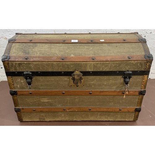 73 - An early 20th century green canvas and wooden banded dome top travel trunk - approx. 56cm high x 84c... 