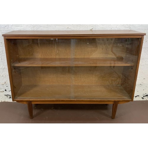 125 - A mid 20th century teak bookcase with two sliding glazed doors - approx. 85cm high x 116cm wide x 27... 