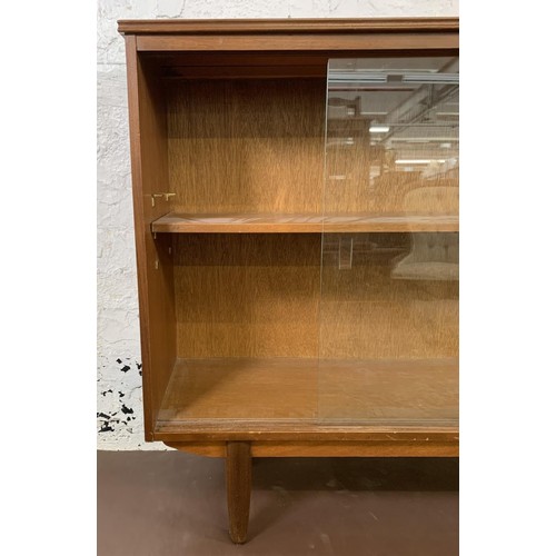 125 - A mid 20th century teak bookcase with two sliding glazed doors - approx. 85cm high x 116cm wide x 27... 