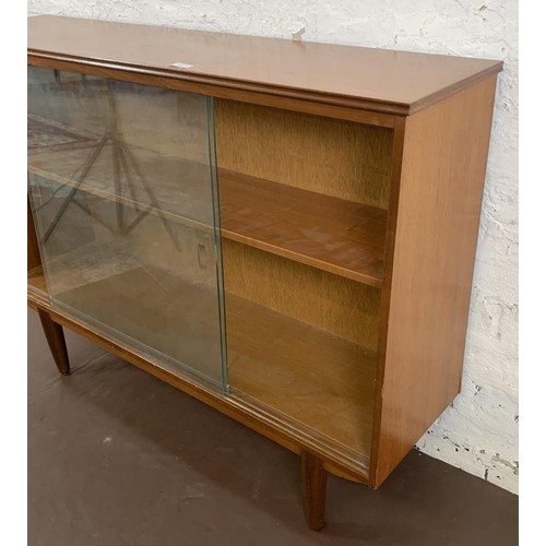 125 - A mid 20th century teak bookcase with two sliding glazed doors - approx. 85cm high x 116cm wide x 27... 