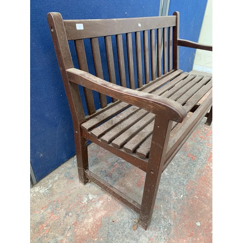 147 - A brown painted wooden slatted garden bench - approx. 87cm high x 122cm wide x 46cm deep