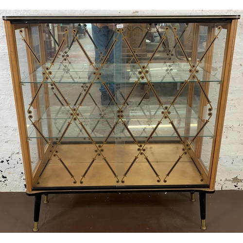 211 - A mid 20th century walnut and glazed display cabinet with two sliding doors, two glazed shelves and ... 