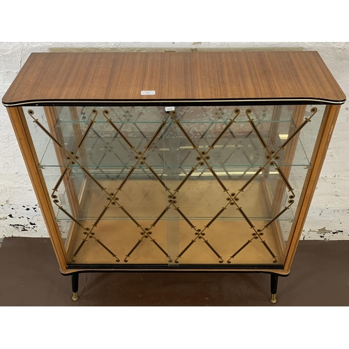 211 - A mid 20th century walnut and glazed display cabinet with two sliding doors, two glazed shelves and ... 