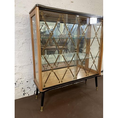 211 - A mid 20th century walnut and glazed display cabinet with two sliding doors, two glazed shelves and ... 