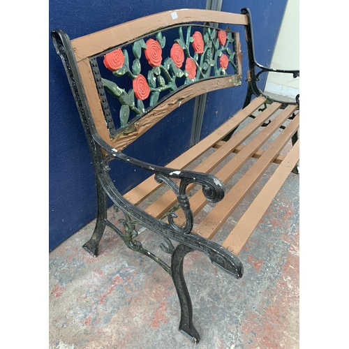 40 - A cast iron and wooden slatted garden bench with rose design back support - approx. 82cm high x 128c... 