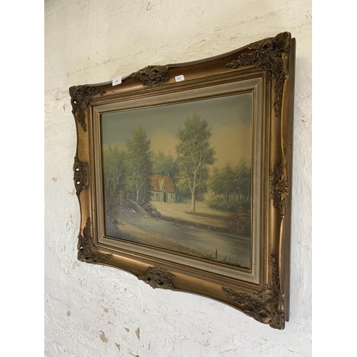 284 - A mid 20th century gilt framed oil on canvas of a riverside scene signed lower left - approx. 58cm h... 