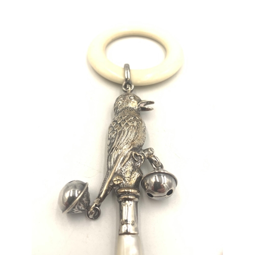 2135 - An antique hallmarked Birmingham silver bird design baby rattle with mother of pearl handle, white b... 