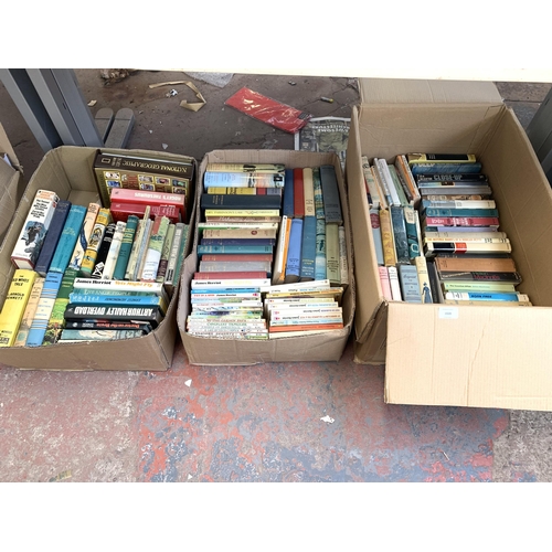 1028 - Three boxes containing books to include authors such as James Herriot, James Milton, Arnold Bennett ... 