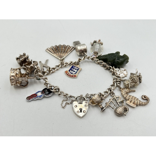 2051 - A hallmarked Birmingham sterling silver charm bracelet with heart shaped padlock clasp and assorted ... 