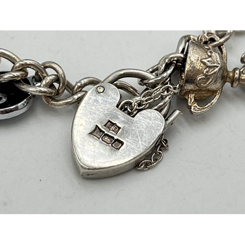 2051 - A hallmarked Birmingham sterling silver charm bracelet with heart shaped padlock clasp and assorted ... 