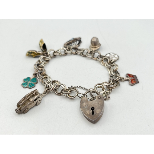 2071 - A hallmarked London sterling silver charm bracelet with heart shaped padlock clasp and assorted char... 