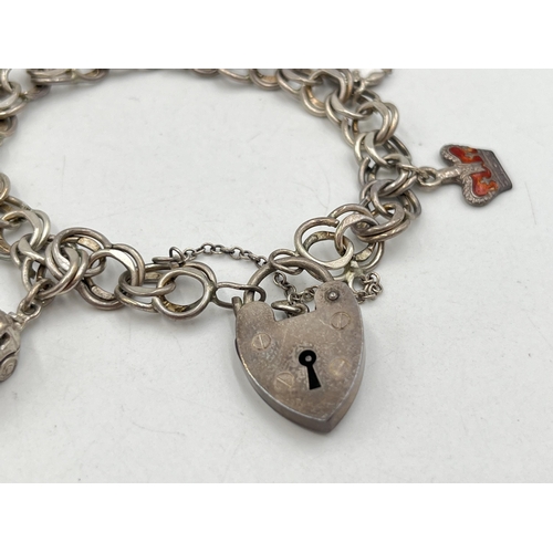 2071 - A hallmarked London sterling silver charm bracelet with heart shaped padlock clasp and assorted char... 