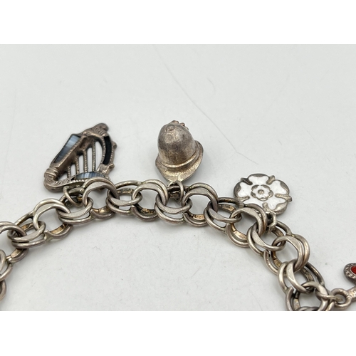 2071 - A hallmarked London sterling silver charm bracelet with heart shaped padlock clasp and assorted char... 