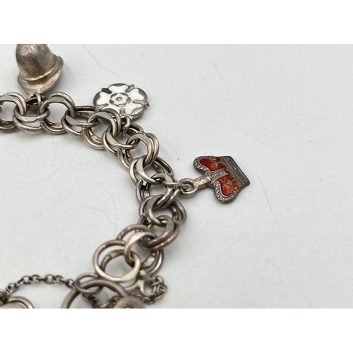 2071 - A hallmarked London sterling silver charm bracelet with heart shaped padlock clasp and assorted char... 