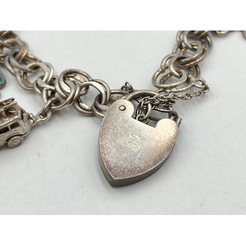 2071 - A hallmarked London sterling silver charm bracelet with heart shaped padlock clasp and assorted char... 