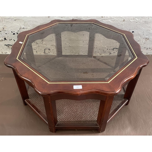 131 - A late 20th century mahogany and smoked glass octagonal serpentine coffee table - approx. 39cm high ... 