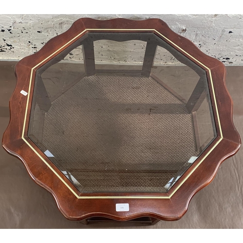 131 - A late 20th century mahogany and smoked glass octagonal serpentine coffee table - approx. 39cm high ... 