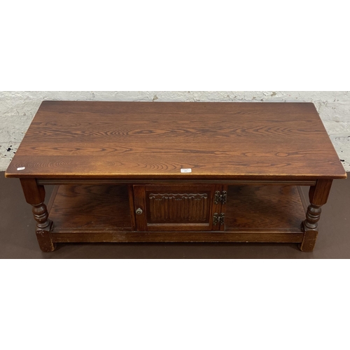 121 - An Old Charm carved oak rectangular coffee table with linenfold cupboard door - approx. 46cm high x ... 