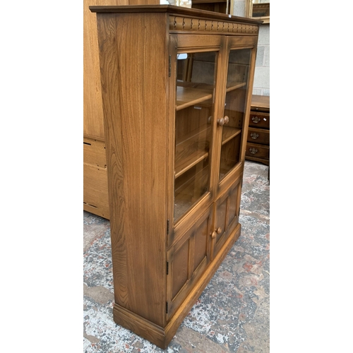 33 - An Ercol Golden Dawn elm glazed bookcase - approx. 138cm high x 100cm wide x 30cm deep