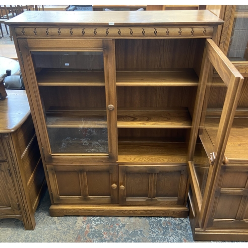 33 - An Ercol Golden Dawn elm glazed bookcase - approx. 138cm high x 100cm wide x 30cm deep