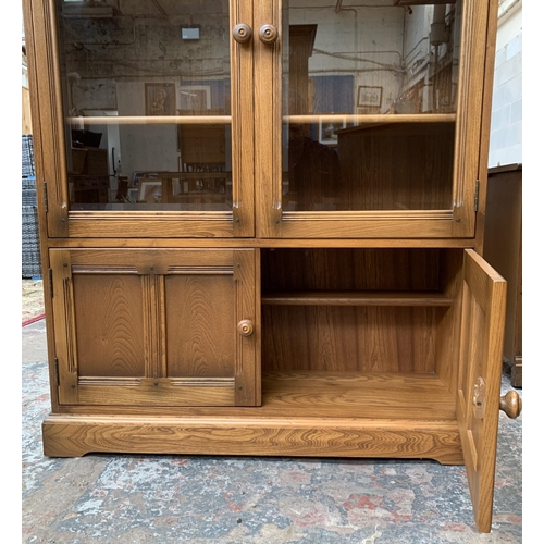 33 - An Ercol Golden Dawn elm glazed bookcase - approx. 138cm high x 100cm wide x 30cm deep