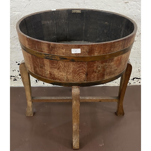 47 - A coopered oak and metal banded planter on wooden stand bearing label 