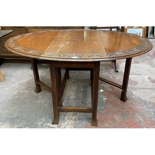 49 - An early 20th century carved oak drop leaf gate leg oval dining table on reeded supports - approx. 7... 