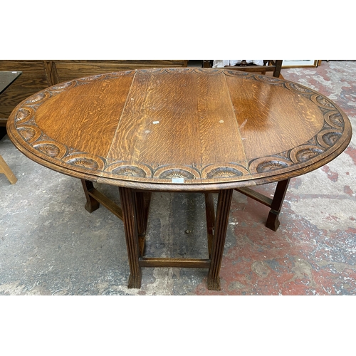 49 - An early 20th century carved oak drop leaf gate leg oval dining table on reeded supports - approx. 7... 