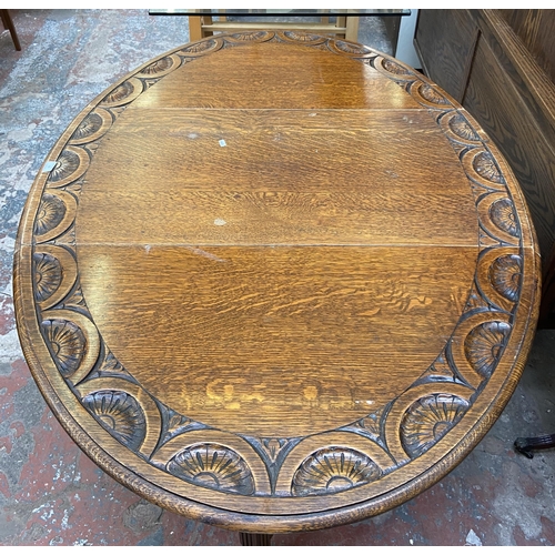 49 - An early 20th century carved oak drop leaf gate leg oval dining table on reeded supports - approx. 7... 