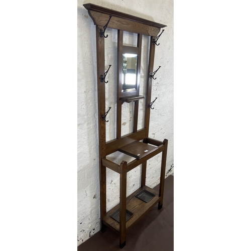 6 - An Arts & Crafts oak hall stand with central bevelled edge mirror and six coat hooks - approx. 185cm... 