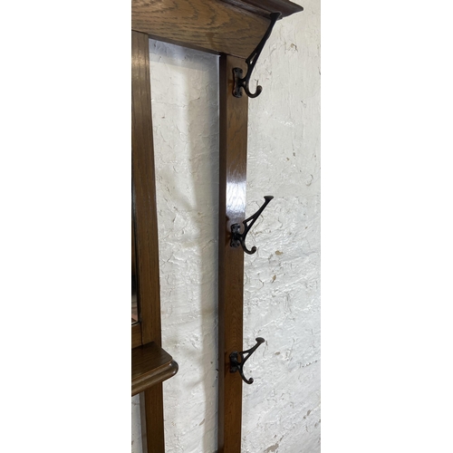 6 - An Arts & Crafts oak hall stand with central bevelled edge mirror and six coat hooks - approx. 185cm... 