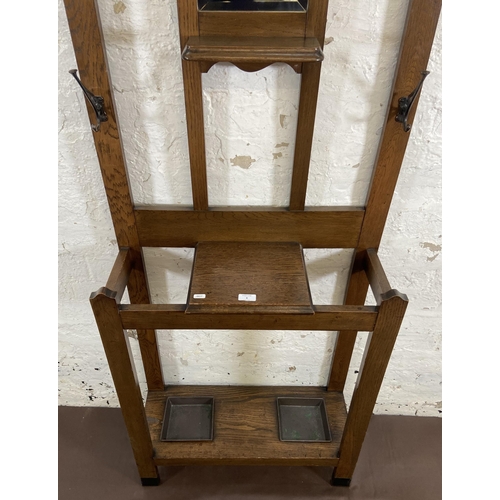 6 - An Arts & Crafts oak hall stand with central bevelled edge mirror and six coat hooks - approx. 185cm... 