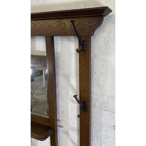 6 - An Arts & Crafts oak hall stand with central bevelled edge mirror and six coat hooks - approx. 185cm... 