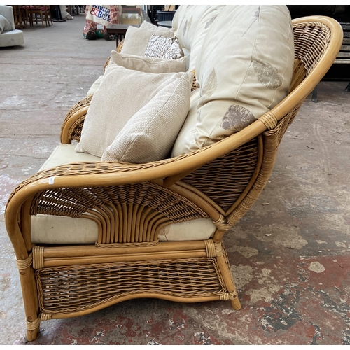 75 - A modern wicker and cane four piece conservatory suite comprising two seater sofa, two armchairs and... 