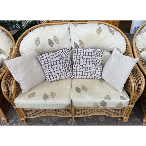 75 - A modern wicker and cane four piece conservatory suite comprising two seater sofa, two armchairs and... 