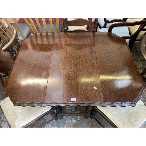 62 - An early 20th century oak pie crust edge drop leaf gate leg dining table on barley twist supports an... 