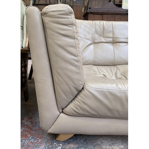 66 - A modern beige leather three piece lounge suite comprising two seater sofa, armchair and footstool