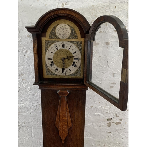 94 - An Art Deco Enfield Clock Co. London Ltd oak cased chiming granddaughter clock with two keys and pen... 