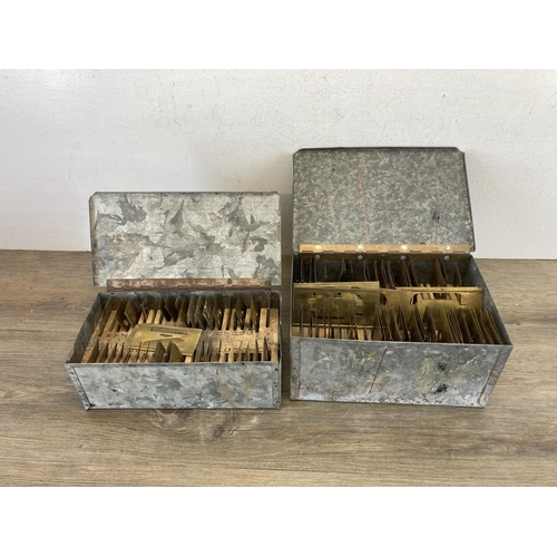 513 - Two galvanized tins containing a collection of brass letter and number stencils