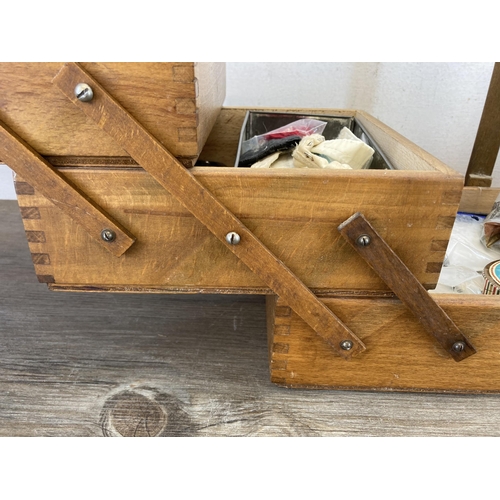 516A - A mid 20th century oak and beech cantilever sewing box containing various sewing accessories to incl... 