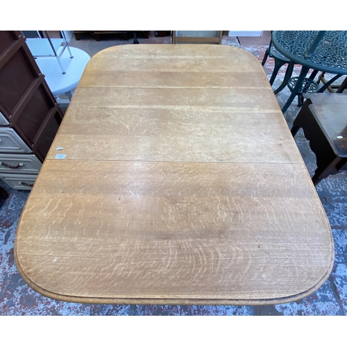 151 - An early 20th century oak drop leaf gate leg dining table on reeded supports