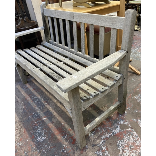 158 - A teak two seater garden bench - approx. 83cm high x 130cm wide x 57cm deep