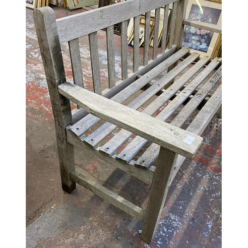 158 - A teak two seater garden bench - approx. 83cm high x 130cm wide x 57cm deep