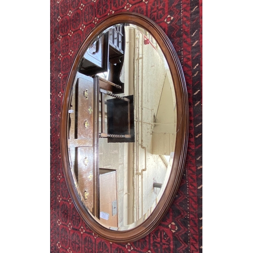 8A - An Edwardian mahogany framed bevelled edge oval wall mirror - approx. 90cm high x 60cm wide