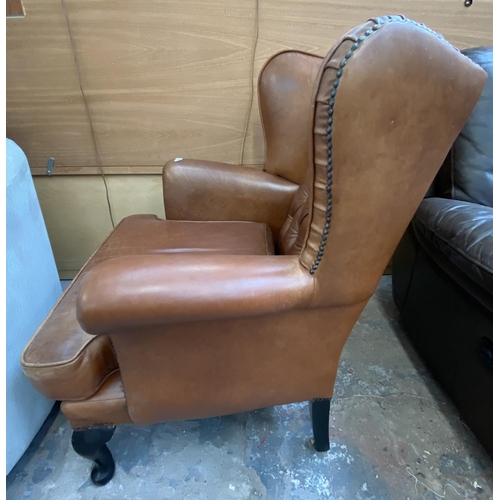 253 - A brown leather Chesterfield wingback armchair on cabriole supports