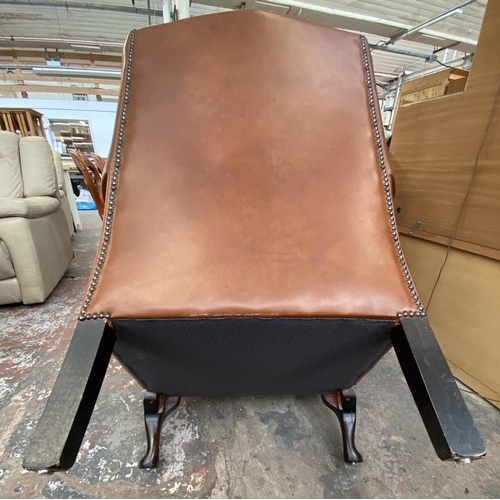 253 - A brown leather Chesterfield wingback armchair on cabriole supports