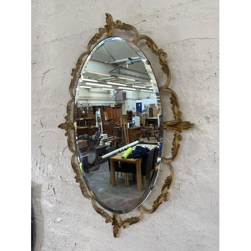 343 - Two mid 20th century oval wall mirrors, one oak framed bevelled edge and one French style metal fram... 