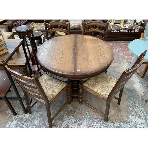 161 - An oak circular extending table on carved baluster support and four chairs - approx. 78cm high x 110... 